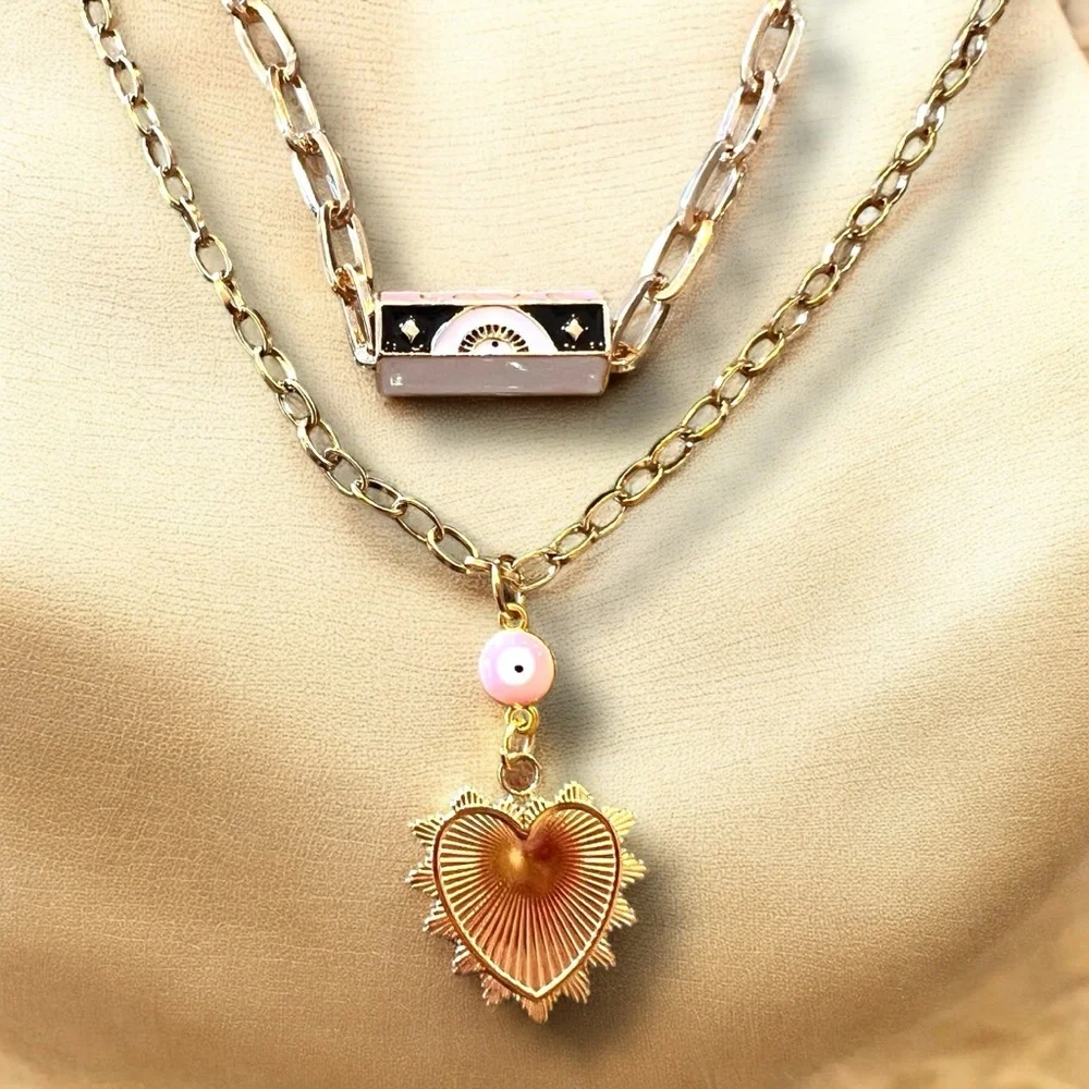 Gold toned chains with black, white, gold, and pastel pink enamel charms.